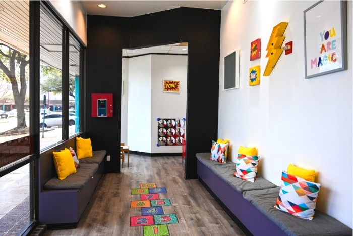 waiting area of dental office with a hopscotch on the floor, fun mirror on the wall, and colorful decorations