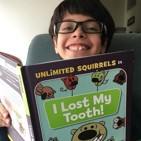 Boy smiles over book about teeth