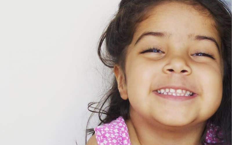 a young girl gives a big smile with dimples
